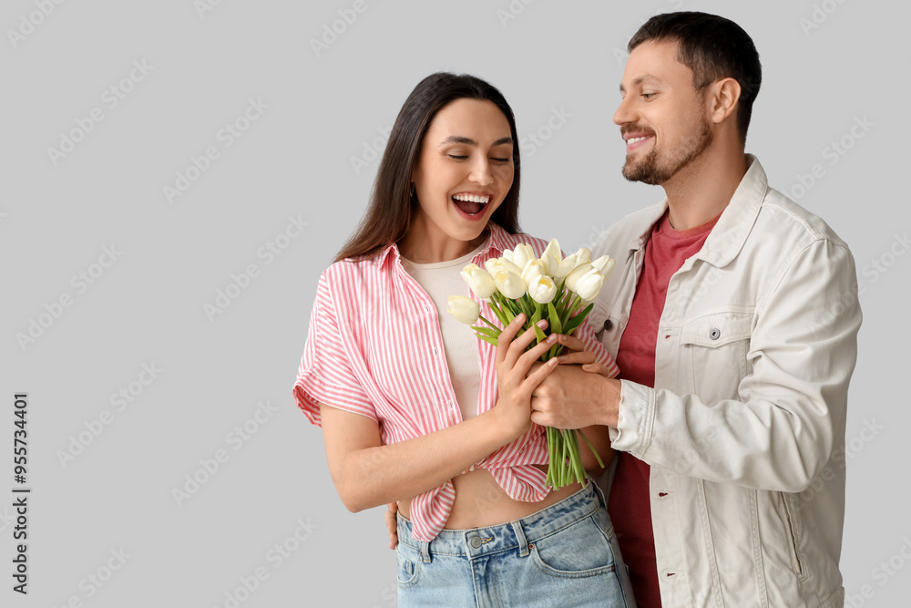 Happy young couple with tulips on light background Happy young couple with tulips on light background