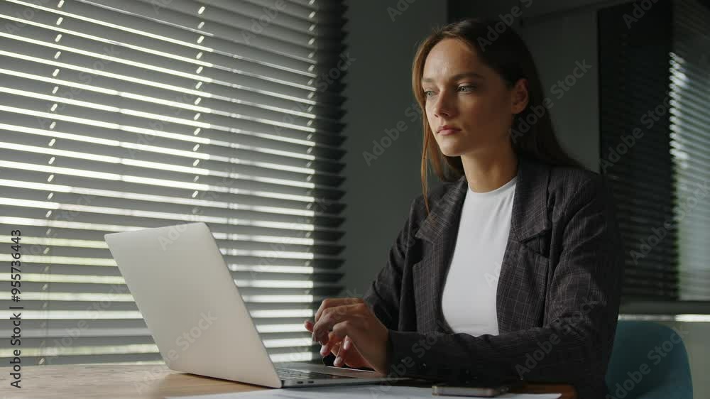 Young concentrated woman working on laptop at desk in home office. Young concentrated woman working on laptop at desk in home office.