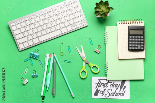 Card with text FIRST DAY OF SCHOOL, different stationery and computer keyboard on green background