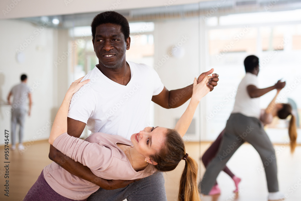 Fototapeta premium Active adult people practicing in modern choreography studio, dancing slow ballroom dances in pairs ..