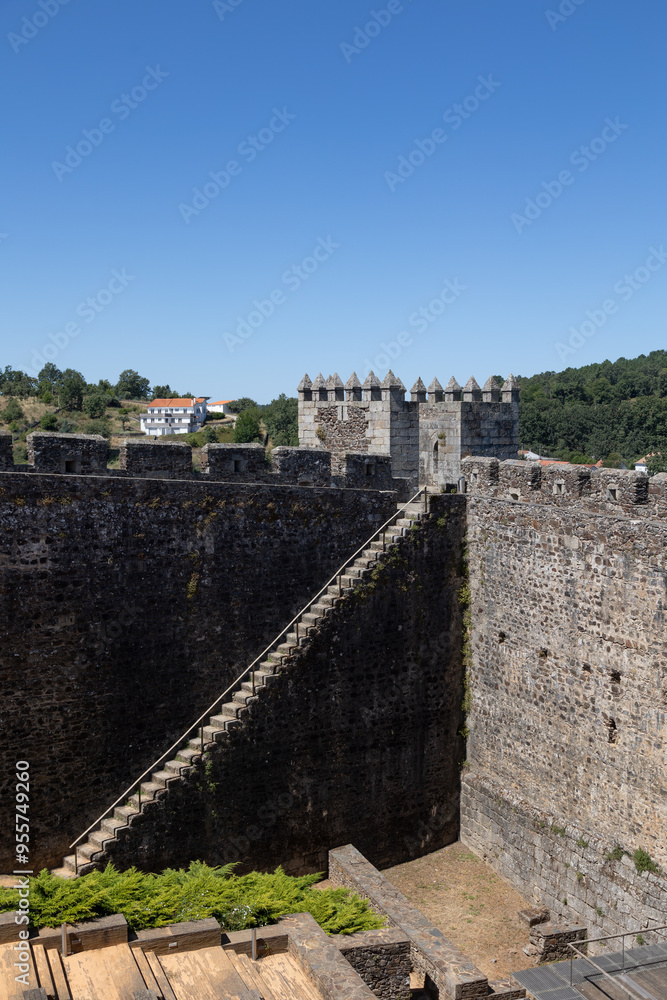 Sabugal Castle in Portugal features imposing stone walls and a historic stone staircase, showcasing its medieval architecture. The image captures the fortress under a clear blue sky Sabugal Castle in Portugal features imposing stone walls and a historic stone staircase, showcasing its medieval architecture. The image captures the fortress under a clear blue sky