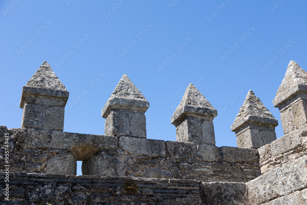 Naklejka premium Sabugal Castle in Portugal features imposing stone walls and a historic stone staircase, showcasing its medieval architecture. The image captures the fortress under a clear blue sky