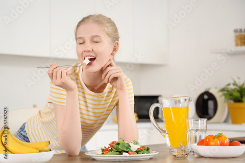 Young woman eating salad wi...