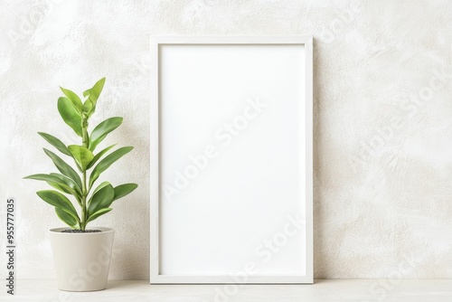 A minimalist setting featuring a blank picture frame next to a potted plant on a textured wall