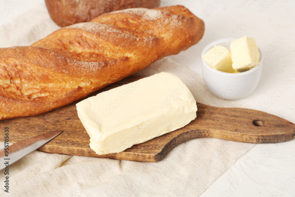 Wooden board with fresh butter and bread on light table Wooden board with fresh butter and bread on light table