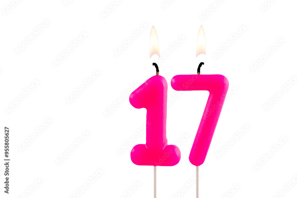 Pink number 17 birthday candle lit on white background Pink number 17 birthday candle lit on white background