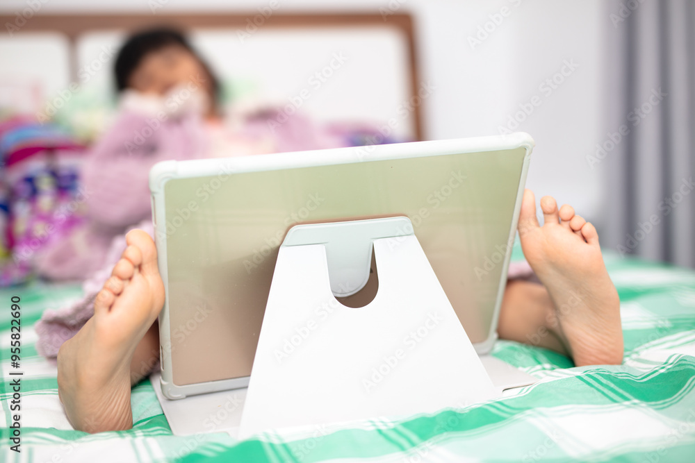 Little girl watching iPad on bed