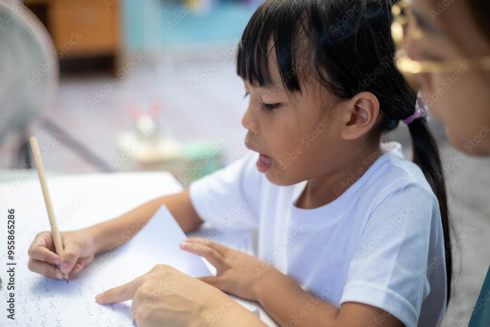 A young girl is sitting at a desk with a pencil and a piece of paper A young girl is sitting at a desk with a pencil and a piece of paper