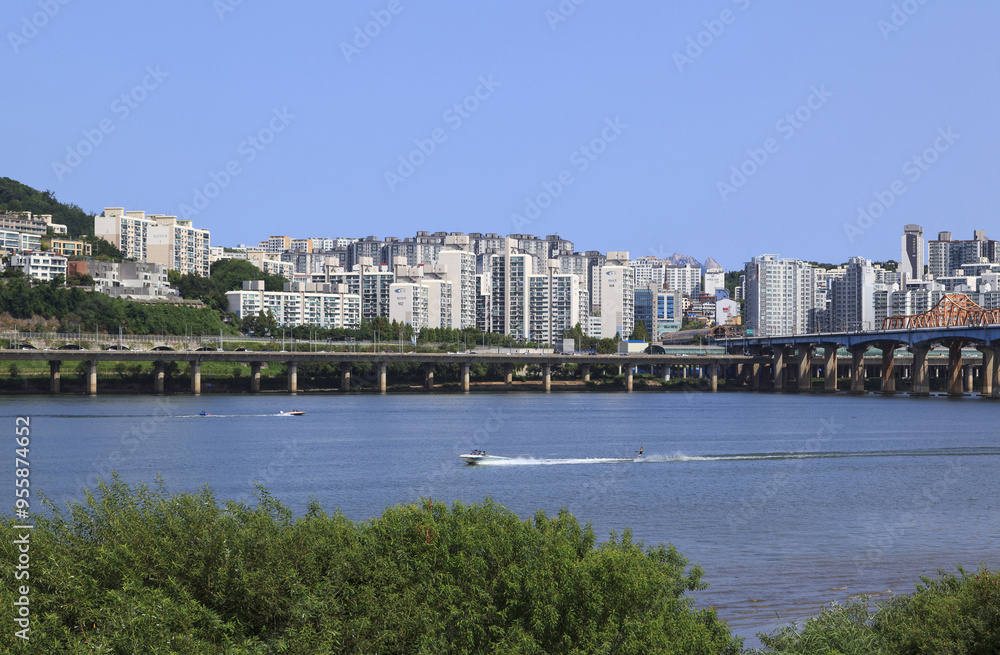 Obraz premium Oksu-dong, Seongdong-gu, Seoul, South Korea - August 15, 2021: Summer view of water ski and motorboat on Han River against Gangbyeon Expressway and highrise apartments