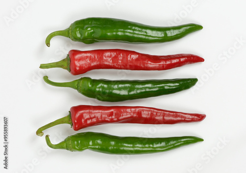 Close-up of raw hot peppers in a line with three green and two red on white floor, South Korea