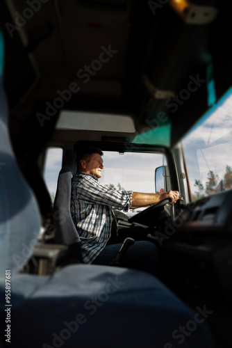 Vertical image, truck driver in the cabin on bright sunny day, looking ahead 