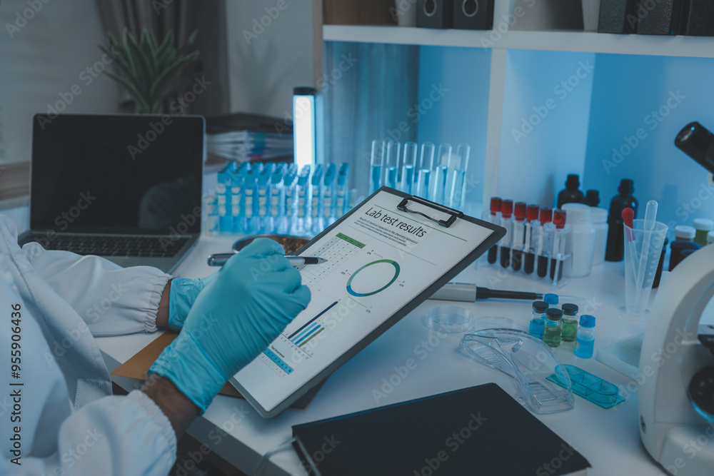 A scientist is reviewing lab results and documents receives from researchers involved in chemical testing, chemist is concentrating on reading test results document A scientist is reviewing lab results and documents receives from researchers involved in chemical testing, chemist is concentrating on reading test results document