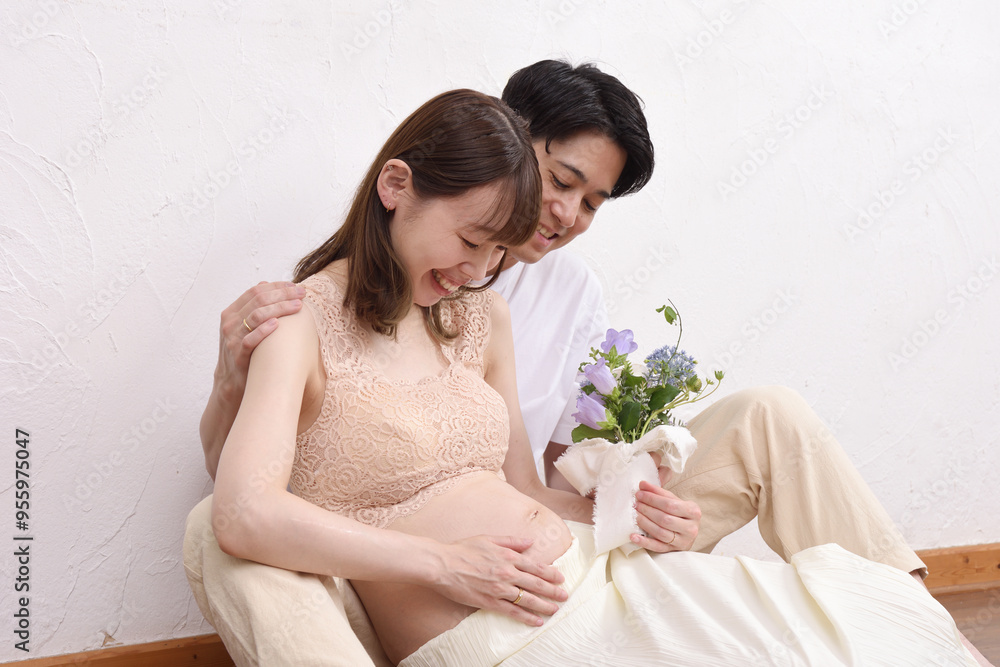 妊娠した若い妻と花束を持って寄り添う夫