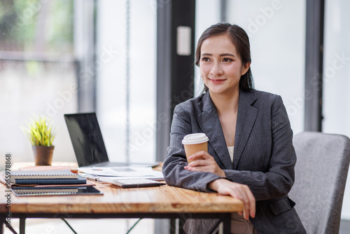 Happy Asian Business woman using calculator and laptop for doing math finance on an office desk, tax, report, accounting, statistics, and analytical research concept