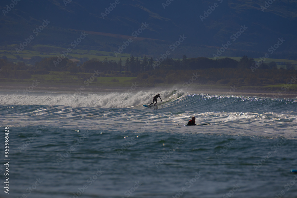 Fototapeta premium yellowish-white waves with surfers against a blue sky. 