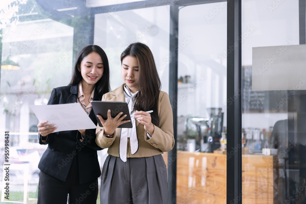 Two Asian young businesswomen using tablet with analyzing financial charts in the modern office, Business financial documents and planning idea project concept. Two Asian young businesswomen using tablet with analyzing financial charts in the modern office, Business financial documents and planning idea project concept.