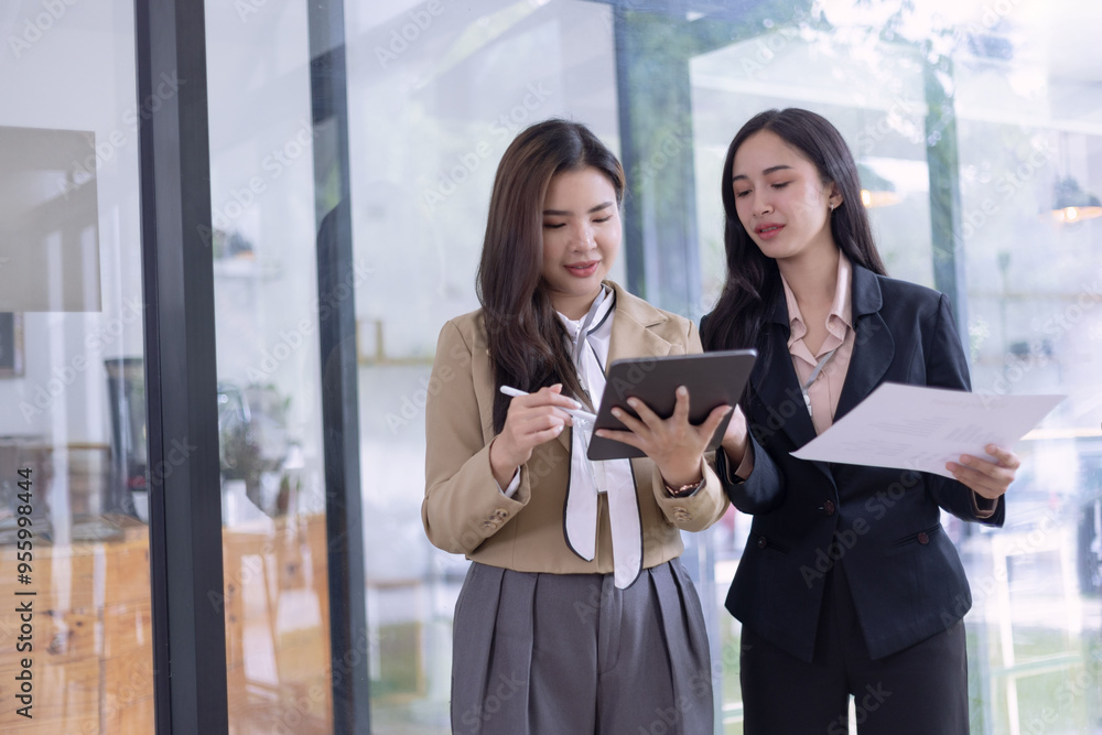 Two Asian young businesswomen using tablet with analyzing financial charts in the modern office, Business financial documents and planning idea project concept. Two Asian young businesswomen using tablet with analyzing financial charts in the modern office, Business financial documents and planning idea project concept.