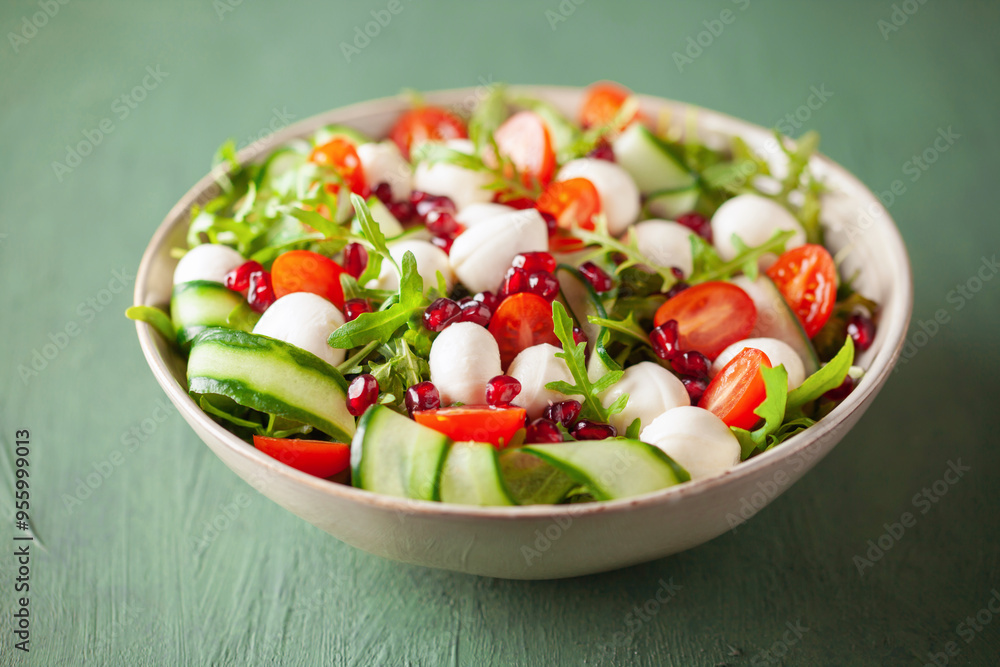 Vegetable salad with cheese and pomegranate grains on a green background Vegetable salad with cheese and pomegranate grains on a green background