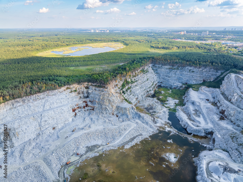 Naklejka premium Stone quarry in the forest. Flying over the summer mixed forest during sunset. The surroundings of Yekaterinburg. Ural, Russia, Aerial View