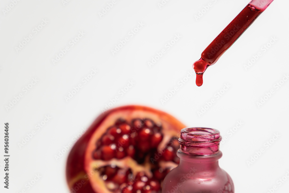 pomegranate extract in glass dropper bottle with a pipette, isolated on white background pomegranate extract in glass dropper bottle with a pipette, isolated on white background
