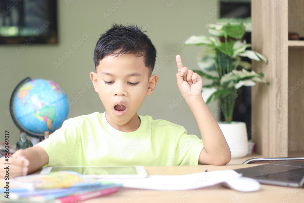 A Happy little asian boy studying online learning class with online video call zoom teacher at home. E-learning or Home schooling education concept. A Happy little asian boy studying online learning class with online video call zoom teacher at home. E-learning or Home schooling education concept.