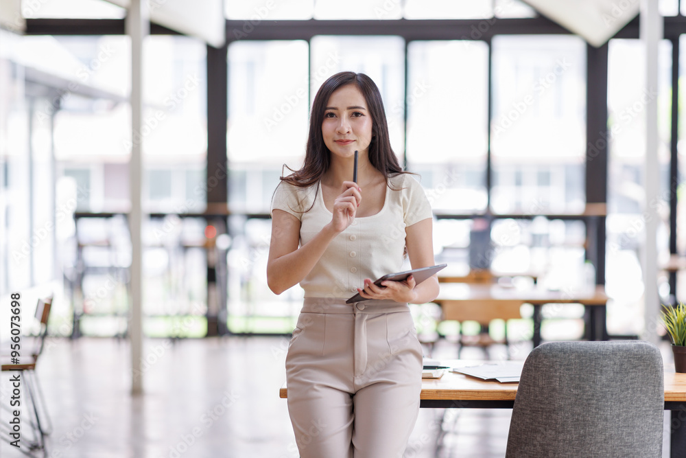 Fototapeta premium Smiling asian female accountant standing with tablet documents indoor workplace office