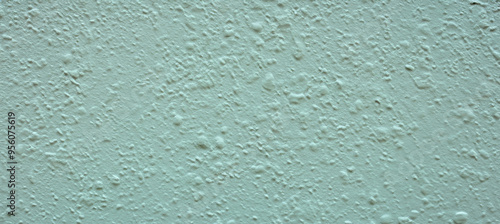 Light green textured wall with bumps and paint drops providing copy space