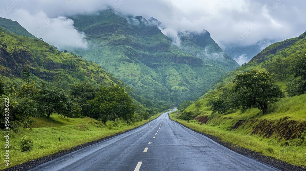 Morning view of an asphalt highway stretching through green mountains, with clouds hovering above Morning view of an asphalt highway stretching through green mountains, with clouds hovering above