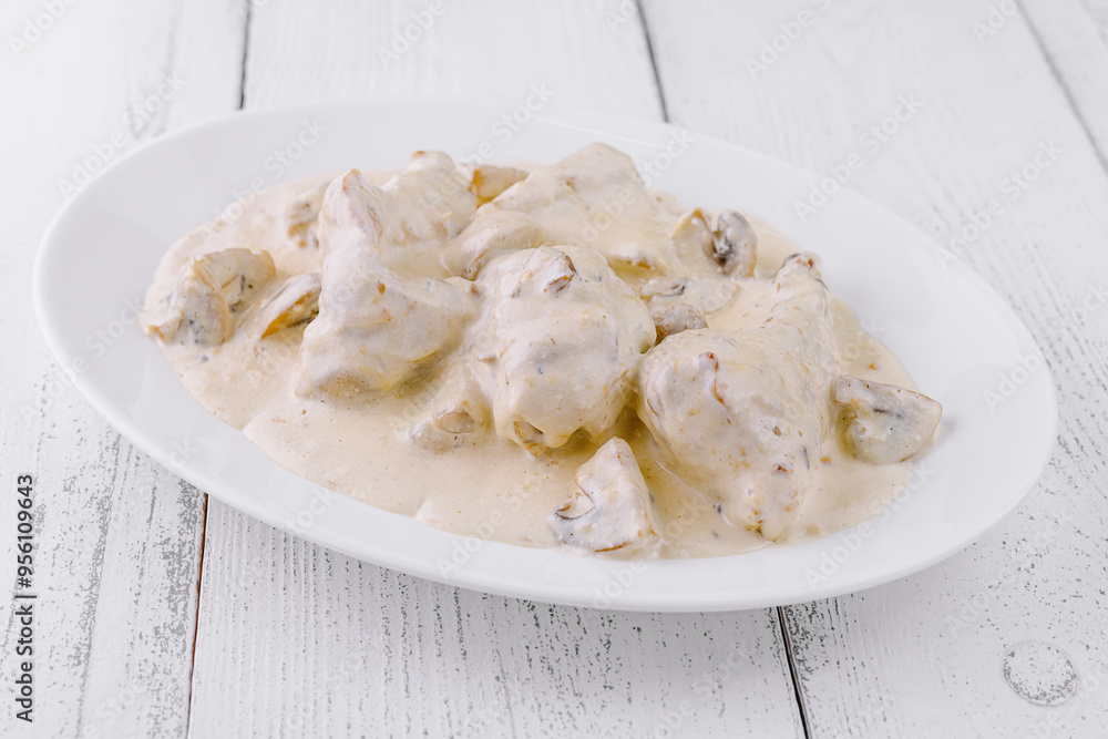 Chicken fricassee with mushrooms in creamy sauce on white plate Chicken fricassee with mushrooms in creamy sauce on white plate