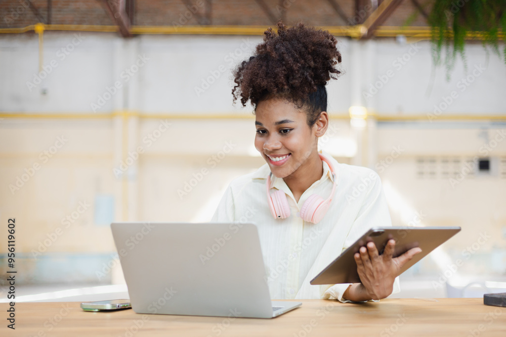African American young woman using tablet with laptop computer. African American young woman using tablet with laptop computer.
