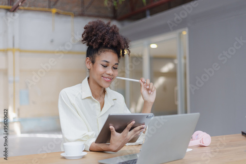 African American young woman using tablet with laptop computer.