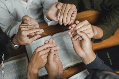 Christians and prayers Group of Christians holding hands praying for faith and Bibles on wooden table for prayer meeting. Sit and pray.