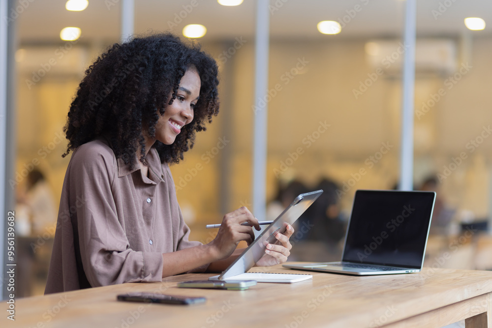 African American businesswoman excited by the good news on the tablet sitting at office desk. African American businesswoman excited by the good news on the tablet sitting at office desk.