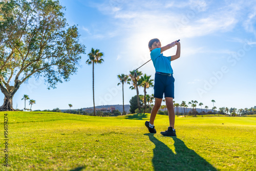 Boy swinging golf alone in a course