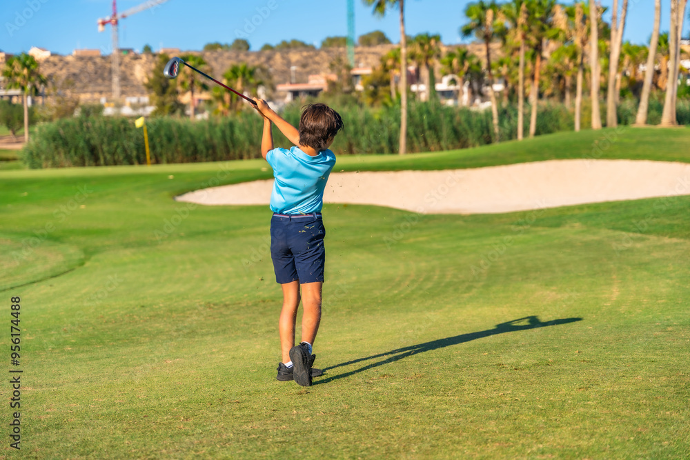 Young boy swinging golf in a green course Young boy swinging golf in a green course
