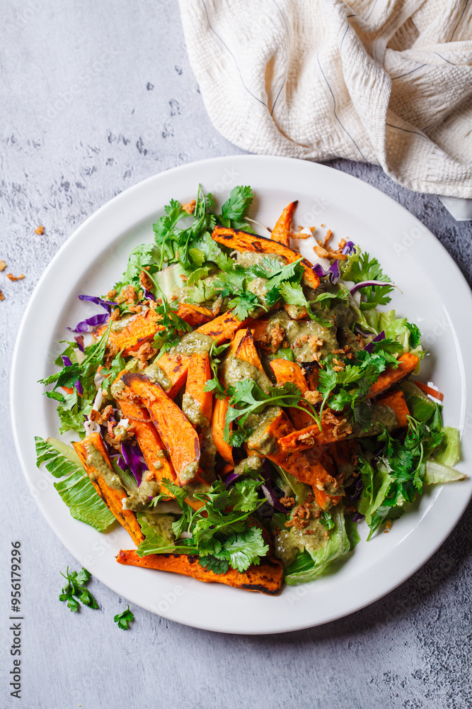 Roasted sweet potato wedges salad with pesto tahini dressing.