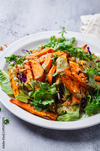 Roasted sweet potato wedges salad with pesto tahini dressing.