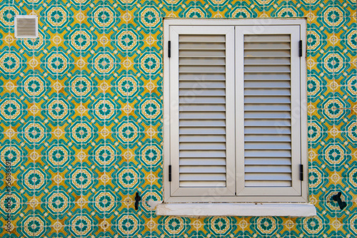 typical geometric  colorful tile Azulejos  mosaic on facade with window closed of a house in Portugal
