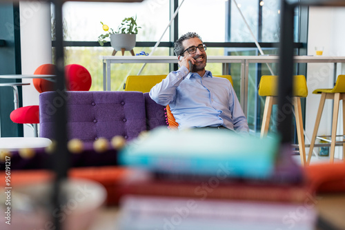 Happy businessman talking on smart phone at co working space