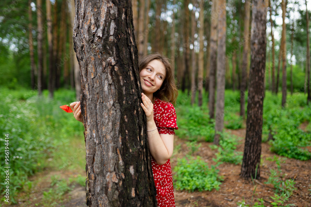 Smiling woman standing near tree trunk in forest Smiling woman standing near tree trunk in forest