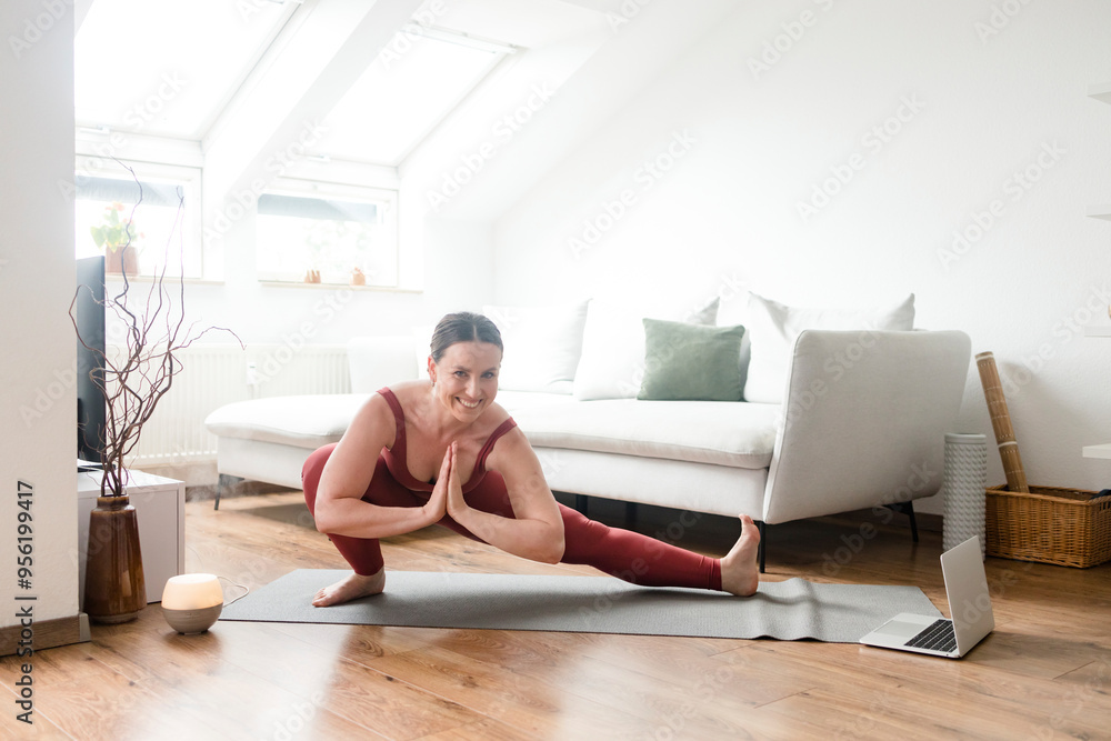 Smiling woman doing side lunge pose on yoga mat at home Smiling woman doing side lunge pose on yoga mat at home