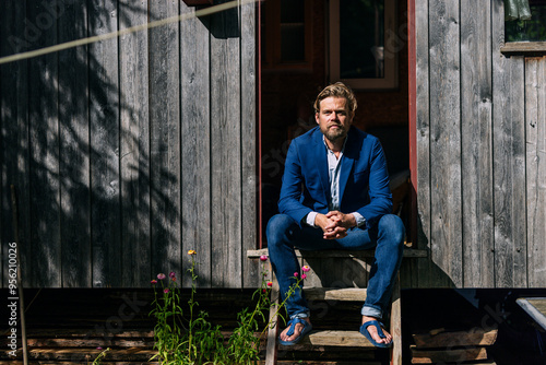 Wallpaper Mural Mature businessman sitting with hands clasped at doorway of log cabin Torontodigital.ca