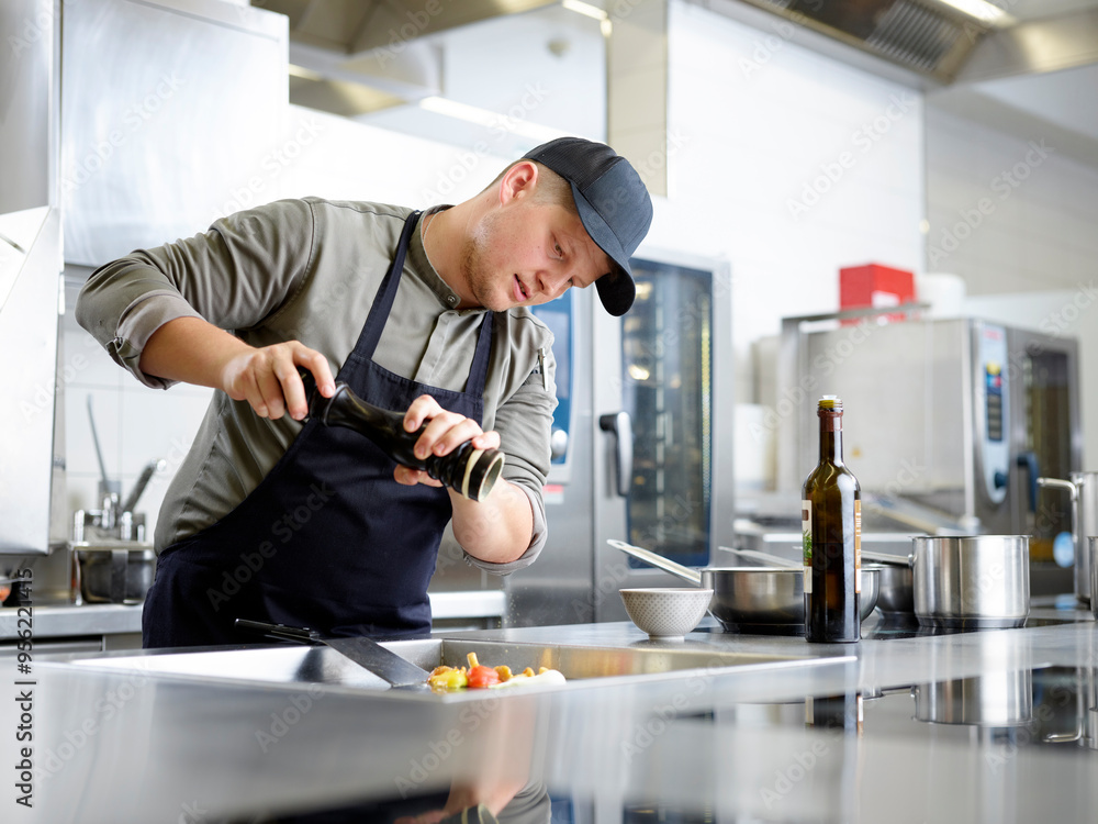Chef adding pepper on meal in kitchen at restaurant Chef adding pepper on meal in kitchen at restaurant