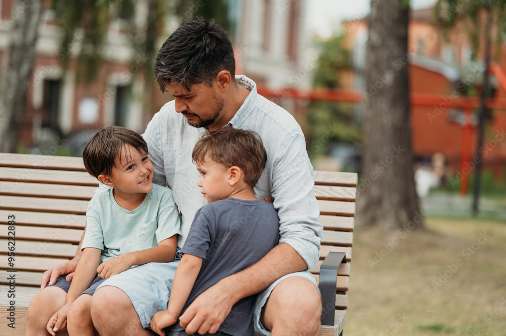 Father sitting with sons on park bench Father sitting with sons on park bench