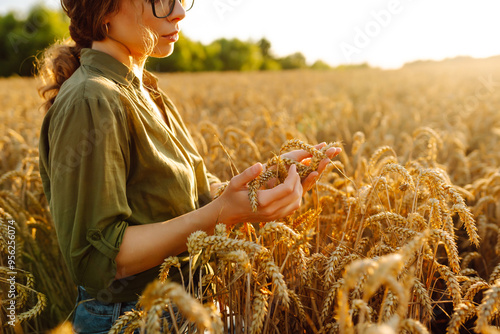 Photography A woman farmer examines golden wheat crops in a sunlit field during the harvest season, appreciating the beauty of nature