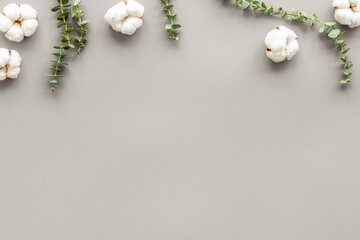 Flowers border with green eucalyptus and cotton flowers on grey background top view copy space. Blog mockup