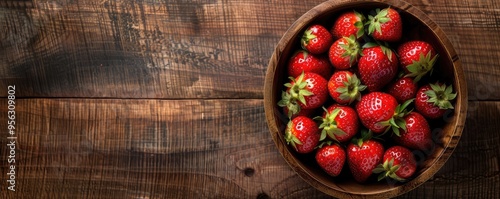 Beautifully arranged ripe strawberries in a rustic bowl on a wooden table, depicting healthy and natural food.