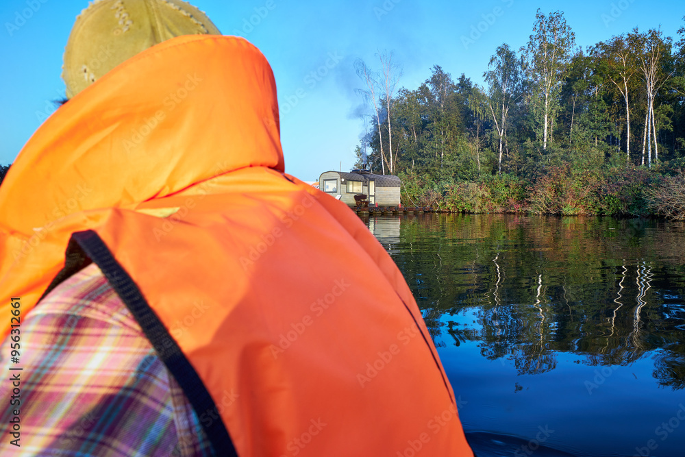 close-up of a man in an orange vest floating in a boat on a river close-up of a man in an orange vest floating in a boat on a river
