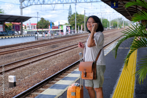 Woman standing on a railway platform, waiting for her train to arrive photo