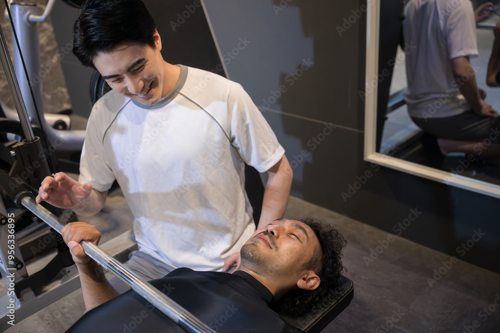 Obraz premium Personal trainer teaching bench press with a smile at a training gym.